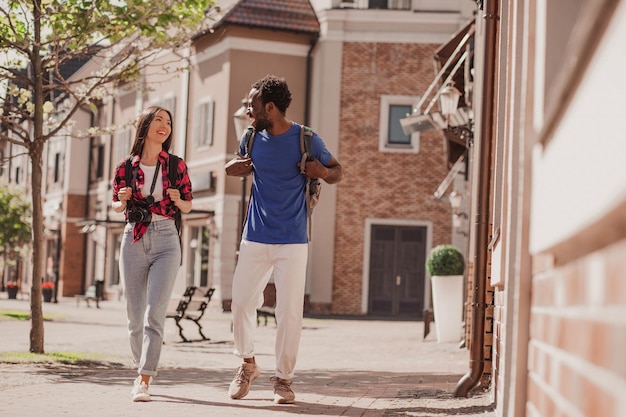 Photo plan complet d'un couple multiracial de touristes marchant sans la ville et parlant