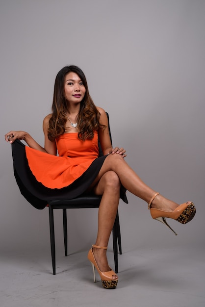 Plan complet du corps d'une femme asiatique assise sur une chaise