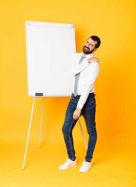 Plan complet d'un homme d'affaires donnant une présentation sur un tableau blanc sur fond jaune isolé souffrant de douleur à l'épaule pour avoir fait un effort