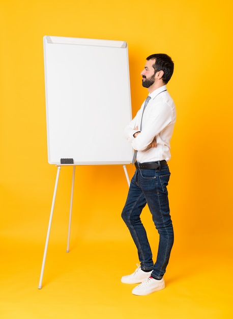 Plan complet d'un homme d'affaires donnant une présentation sur un tableau blanc par-dessus un jaune isolé en position latérale