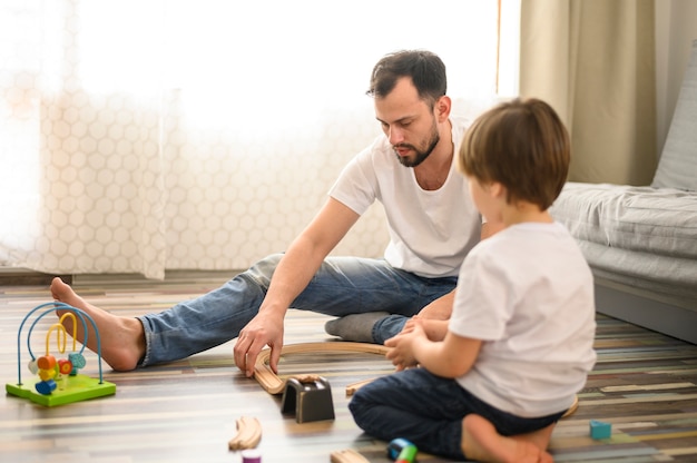 Photo plan complet père jouant avec son fils sur le sol