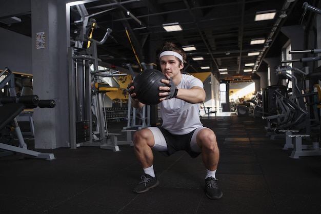 Plan complet d'un sportif faisant des squats avec médecine-ball