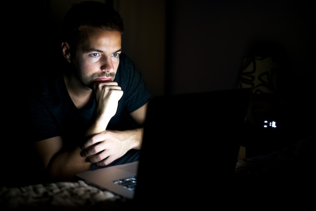 Plan de côté d'un bel homme barbu en t-shirt en regardant un film