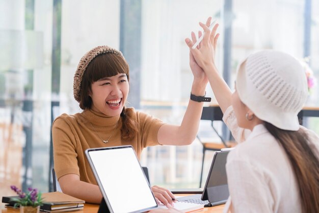 Plan de deux jeunes femmes travaillant ensemble sur une tablette numérique. Des femmes cadres créatives se réunissant dans un bureau à l'aide d'un tablet pc et souriant.