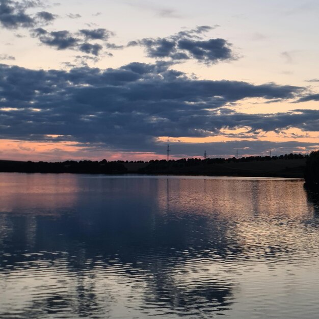 Un plan d'eau avec des arbres et des nuages dans le ciel