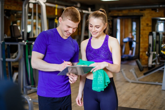 Plan d&#39;un entraîneur personnel aidant un membre du gymnase avec son plan d&#39;exercices.