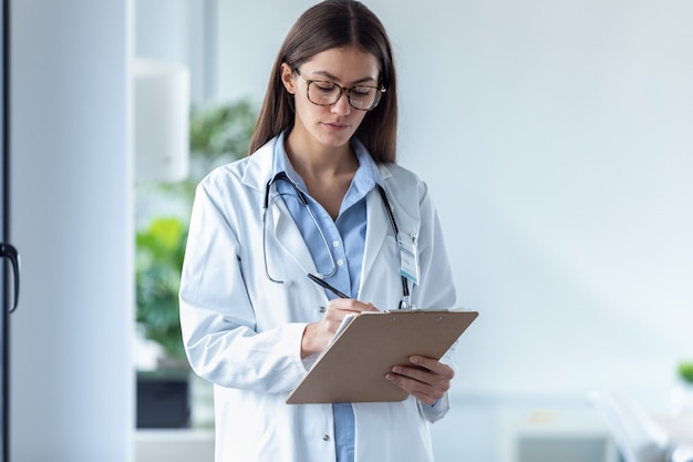 Plan d'une femme médecin concentrée avec des lunettes examinant des rapports médicaux dans le bureau de l'hôpital.