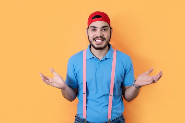 Plan d'un homme heureux avec barbe haussant les bras ouverts sur fond jaune regardant la caméra