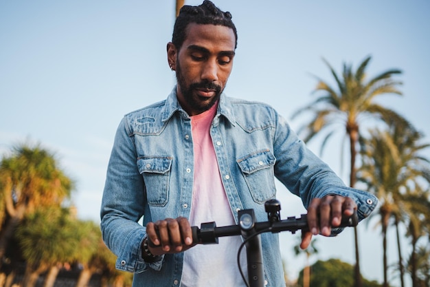 Plan d'un homme tenant le guidon d'un scooter électrique dans la ville Il vérifie que les freins fonctionnent