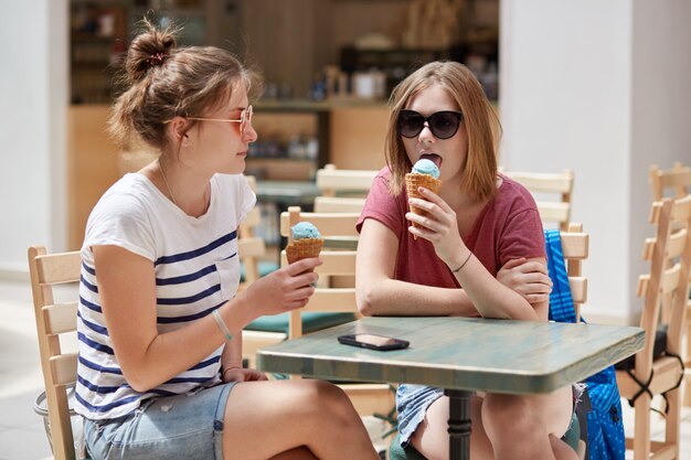 Plan horizontal de jolies jeunes femmes lèchent la glace aux fruits