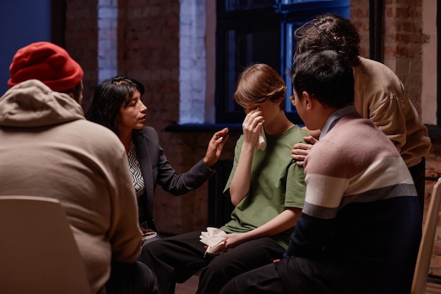 Plan horizontal d'un psychothérapeute professionnel et de clients réconfortant une femme qui pleure pendant le groupe