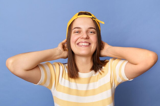 Plan intérieur d'une adolescente caucasienne positive assez heureuse portant une casquette de baseball et un t-shirt décontracté debout isolé sur fond bleu regardant la caméra exprimant le bonheur