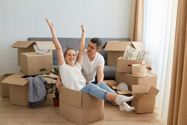 Plan intérieur d'un couple heureux s'amusant avec des boîtes en carton dans une nouvelle maison le jour du déménagement famille satisfaite avec des émotions positives entourées de colis avec des effets personnels