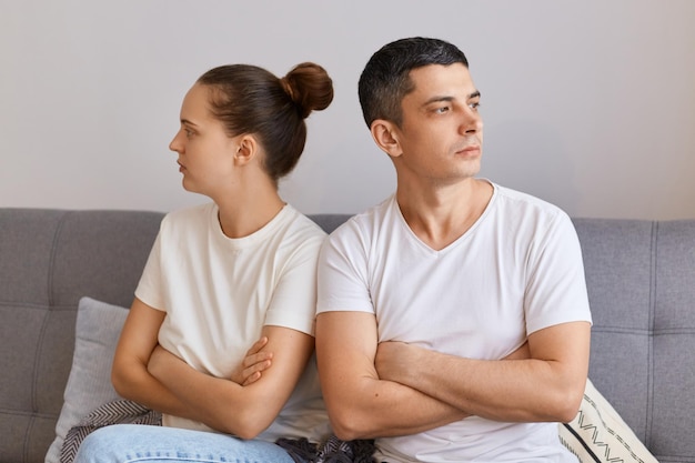 Plan intérieur d'une jeune femme et d'un homme malheureux ne parlant pas après une querelle assis sur un canapé séparément dos à dos une femme et un mari frustrés s'ignorant mutuellement problème relationnel