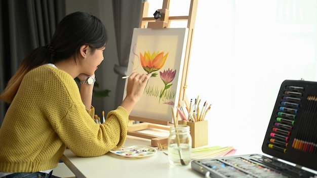 Plan d'une jeune artiste féminine travaille à la peinture en studio