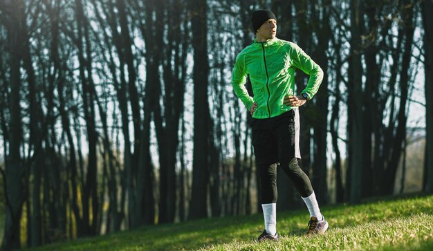 Plan d'un jeune coureur de remise en forme debout à l'extérieur dans le parc après avoir fait du jogging Jeune homme athlétique confiant prêt à faire de l'exercice