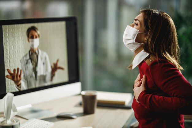 Plan d'une jeune femme ayant une consultation en ligne avec son médecin sur un ordinateur.