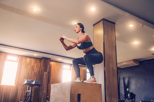 Plan d'une jeune femme travaillant avec une boîte à la salle de sport