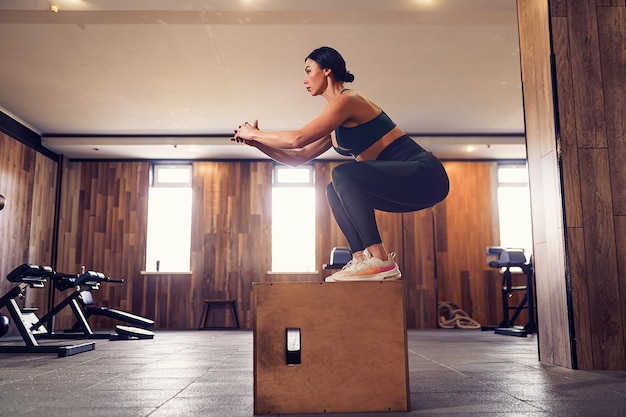 Plan d'une jeune femme travaillant avec une boîte à la salle de sport