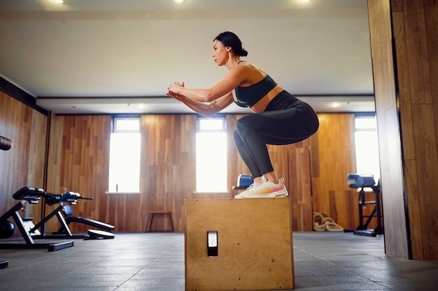 Plan d'une jeune femme travaillant avec une boîte à la salle de sport