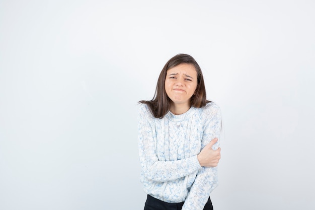 Plan d'une jeune fille en pull qui a mal au bras.