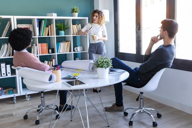 Plan de jeunes entrepreneurs occasionnels travaillant et parlant de leur nouvelle entreprise ensemble au bureau.