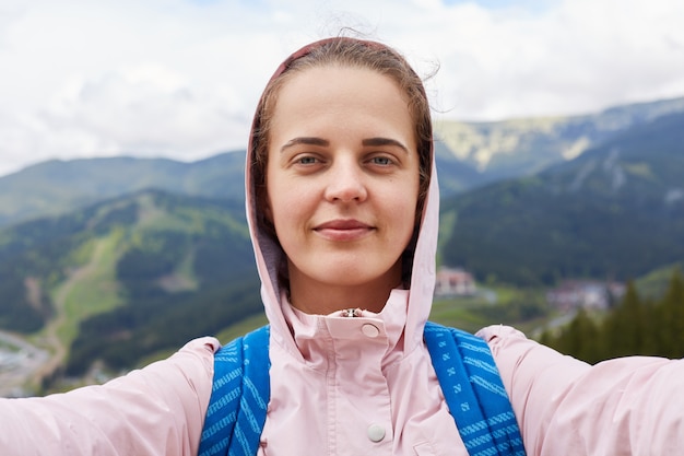 Plan d'une jolie jeune touriste qui fait un selfie en montagne. Voyageur femme ayant des loisirs actifs dans les montagnes.