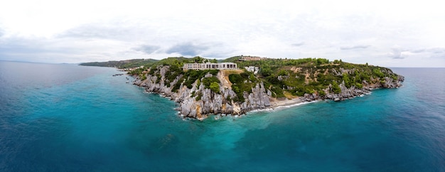 Plan large de la côte grecque de la mer Égée, des bâtiments de Loutra situés près des falaises rocheuses, de la verdure et de l'eau bleue. Vue depuis le drone