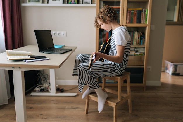 Plan large d'une préadolescente apprenant à jouer de la guitare lors d'une réunion virtuelle avec un enseignant lors d'un appel vidéo T