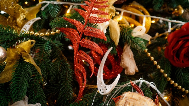 Plan macro sur des décorations de Noël rouges et dorées et des guirlandes sur l'arbre de Noël.