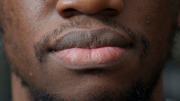 Plan macro sur un jeune homme souriant devant la caméra, ayant une barbe aux cheveux courts et des dents blanches. Personne authentique montrant un sourire candide, avec une peau saine et naturelle et une coupe propre du visage. Fermer.