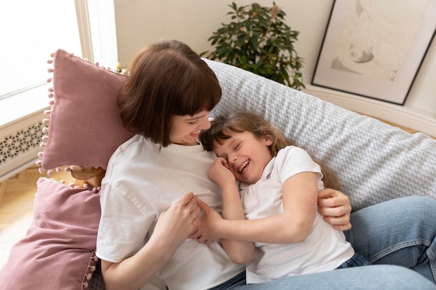 Photo plan moyen mère et fille allongée sur un canapé