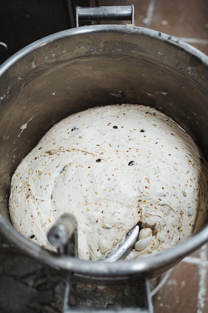 Plan de pâte à pain aux graines déjà pétrie dans un mélangeur en boulangerie