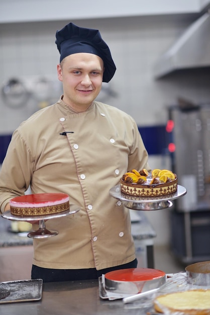 Plan rapproché d'un chef pâtissier masculin concentré décorant la nourriture de gâteau de dessert dans la cuisine