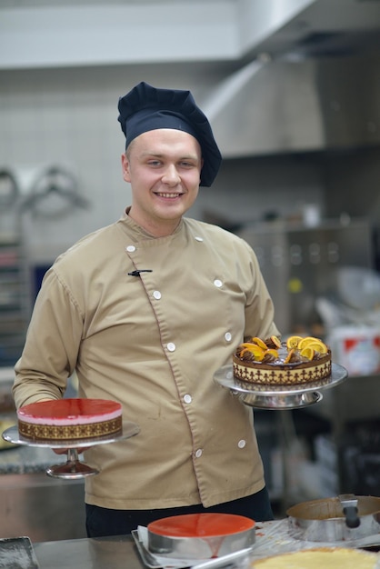 Plan rapproché d'un chef pâtissier masculin concentré décorant la nourriture de gâteau de dessert dans la cuisine