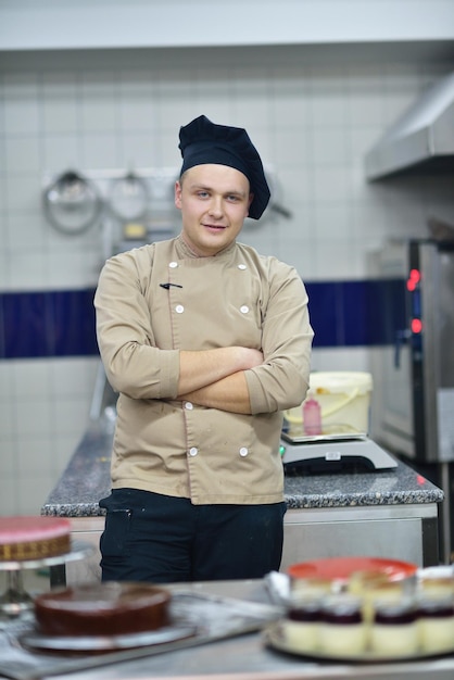 Plan rapproché d'un chef pâtissier masculin concentré décorant la nourriture de gâteau de dessert dans la cuisine