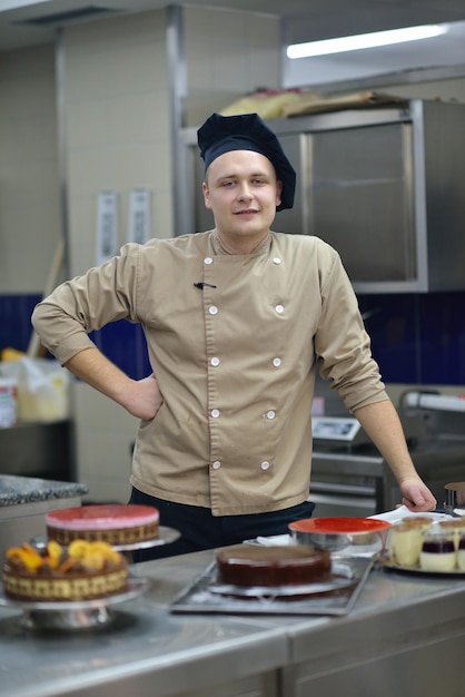 Plan rapproché d'un chef pâtissier masculin concentré décorant la nourriture de gâteau de dessert dans la cuisine