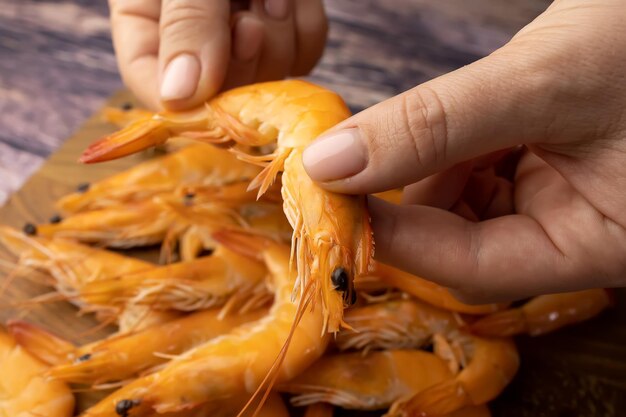 Plan rapproché des crevettes bouillies qui sont nettoyées de la coquille des mains des femmes