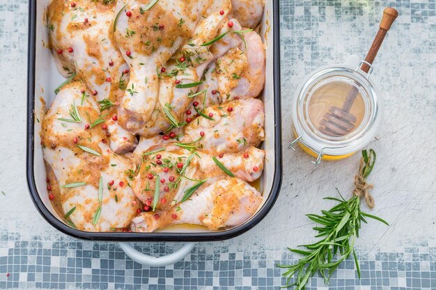 Plan rapproché des cuisses de poulet d'assaisonnement avec du miel et des herbes