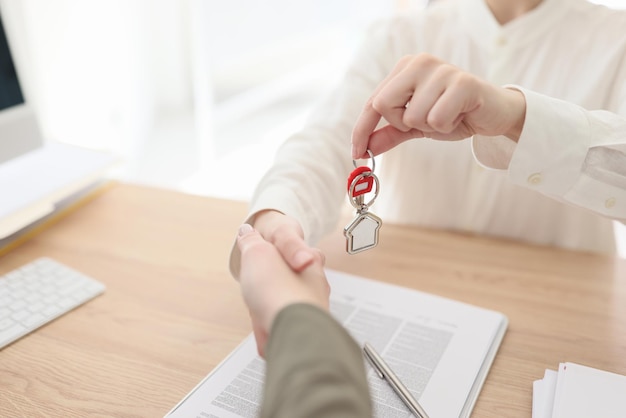 Plan rapproché du directeur immobilier serrant la main avec le client et donnant des clés au nouveau propriétaire réel