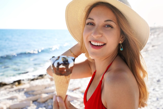 Plan rapproché de femme brésilienne mangeant la crème glacée sur la plage l'été