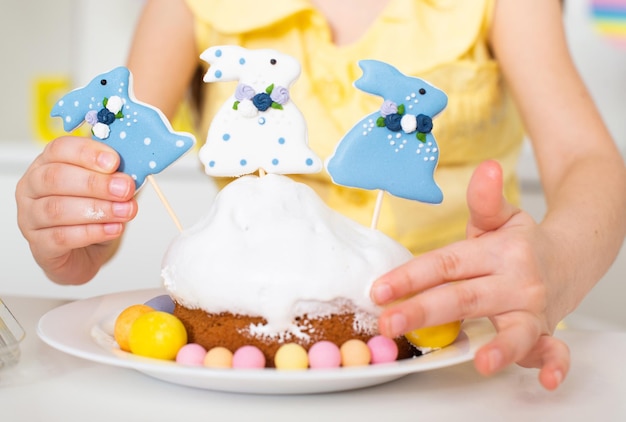 Photo plan rapproché d'un gâteau de pâques décoré de trois lapins et d'oeufs peints cuisson dans la cuisine