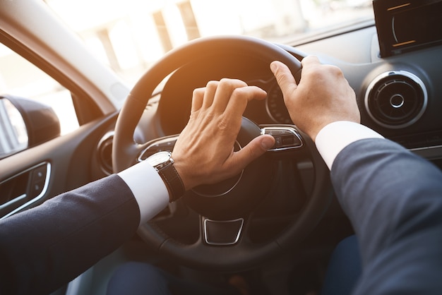 Plan rapproché d'un homme conduisant une voiture avec une main sur un coucher du soleil de bouton de klaxon