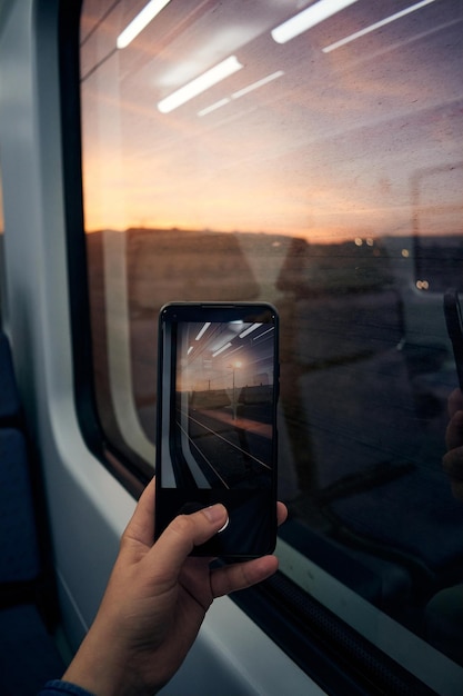 Plan rapproché d'un homme avec un téléphone prenant une photo sur un train