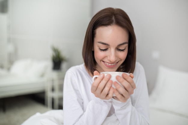 Plan rapproché de jeune dame appréciant le café frais de matin à la maison