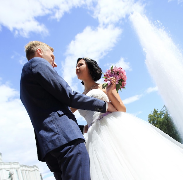 Plan rapproché d'une jeune mariée et d'un marié affectueux sur le fond de la fontaine