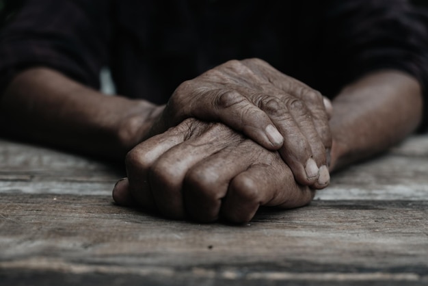 Plan rapproché des mains du vieil homme se reposant sur le bois