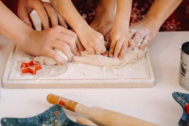 Plan rapproché des mains faisant cuire la pâte sur la table de cuisine de Noël