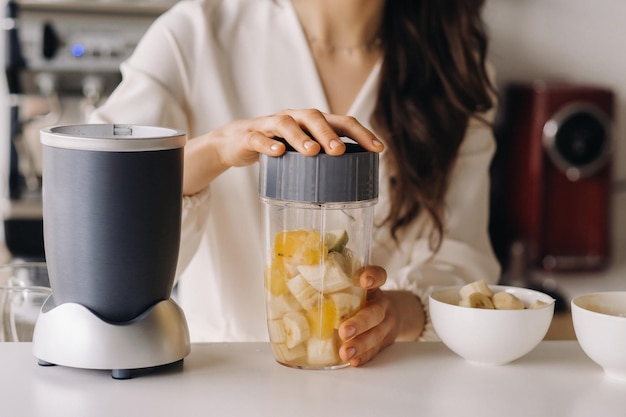 Plan rapproché des mains d'une fille qui fait un cocktail de désintoxication de fruit dans la cuisine Régime pour la perte de poids