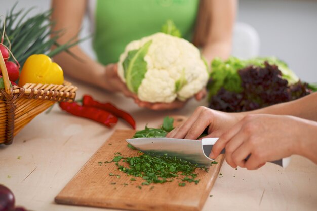 Plan rapproché des mains humaines faisant cuire la salade de légumes dans la cuisine Repas sain et concept végétarien